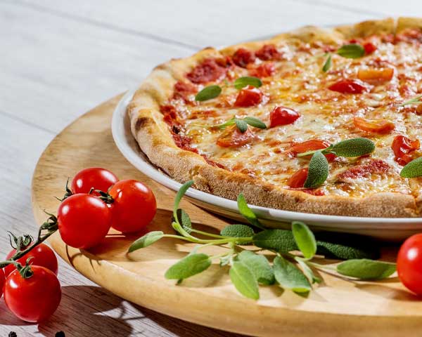 pizza con basilico e pomodorini sul tagliere